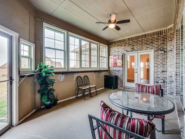 sunroom / solarium with plenty of natural light, a ceiling fan, and french doors