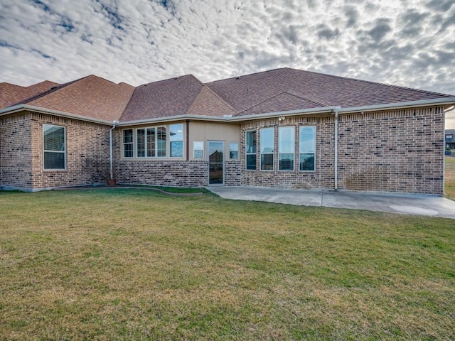 back of property with a yard, brick siding, and a patio