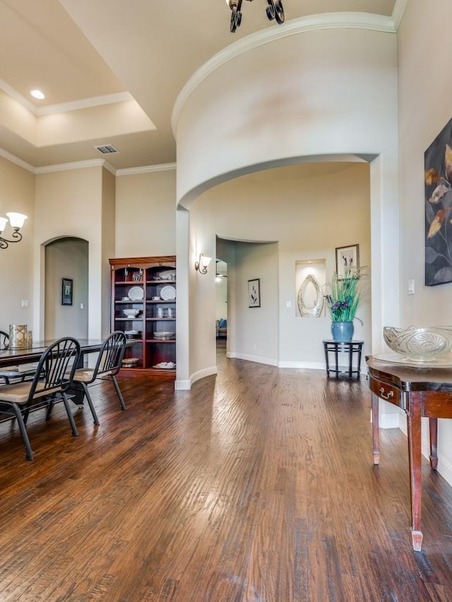 dining area with ornamental molding, dark wood-type flooring, a chandelier, and a tray ceiling