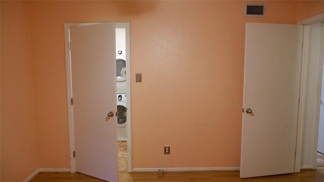 washroom with light wood-type flooring and stacked washer and clothes dryer