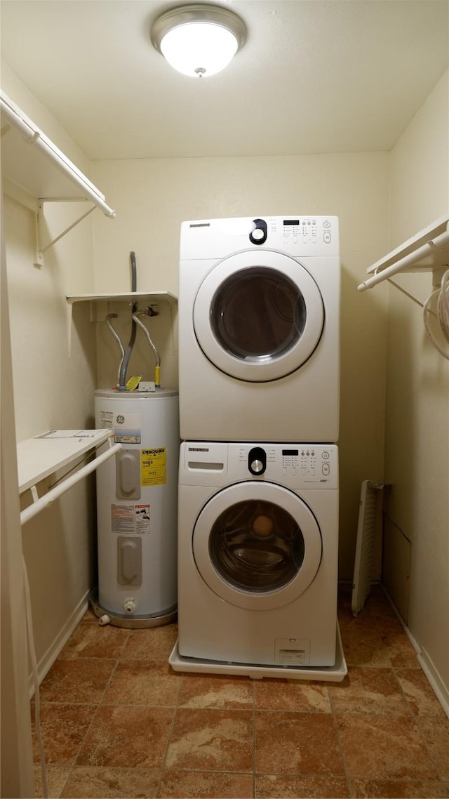 laundry room featuring water heater and stacked washer and dryer