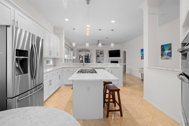 kitchen with a center island, a kitchen bar, stainless steel appliances, kitchen peninsula, and ceiling fan