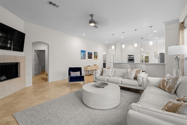 living room featuring ceiling fan and a brick fireplace