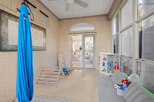 interior space with ceiling fan and brick wall