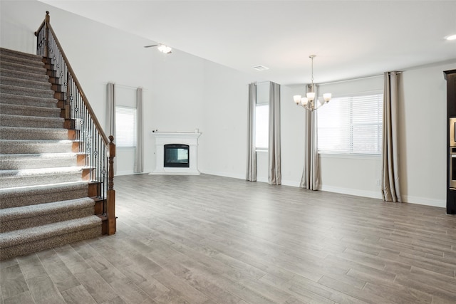 unfurnished living room featuring an inviting chandelier and wood-type flooring