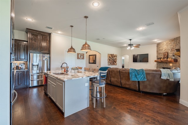 kitchen featuring a kitchen bar, sink, appliances with stainless steel finishes, an island with sink, and light stone countertops