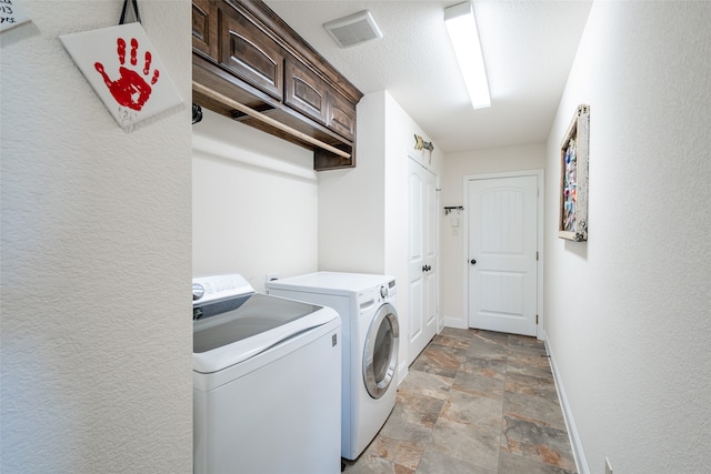 clothes washing area with cabinets and washer and clothes dryer