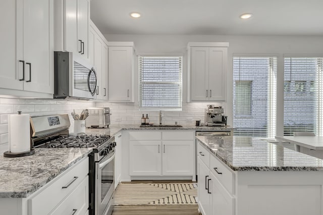 kitchen with stainless steel appliances, white cabinetry, sink, and a healthy amount of sunlight