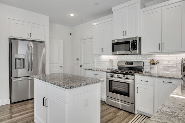 kitchen with light stone counters, a center island, light wood-type flooring, and appliances with stainless steel finishes