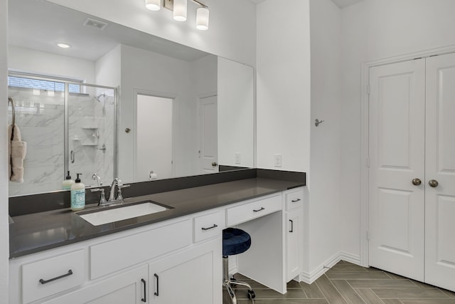 bathroom with vanity, a shower with shower door, and parquet floors