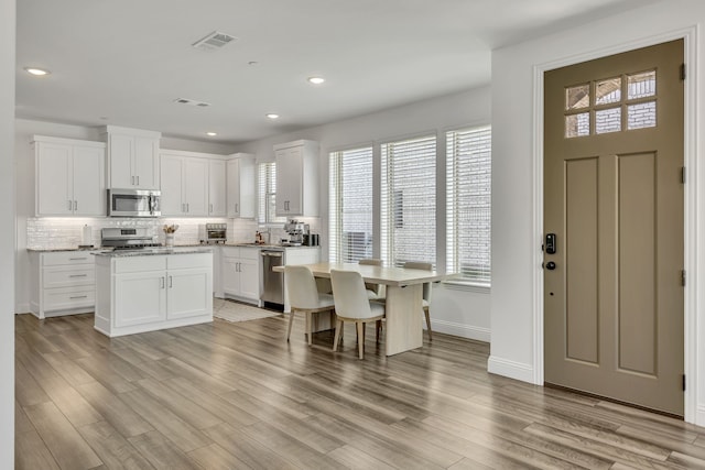 kitchen featuring appliances with stainless steel finishes, a center island, white cabinets, and decorative backsplash