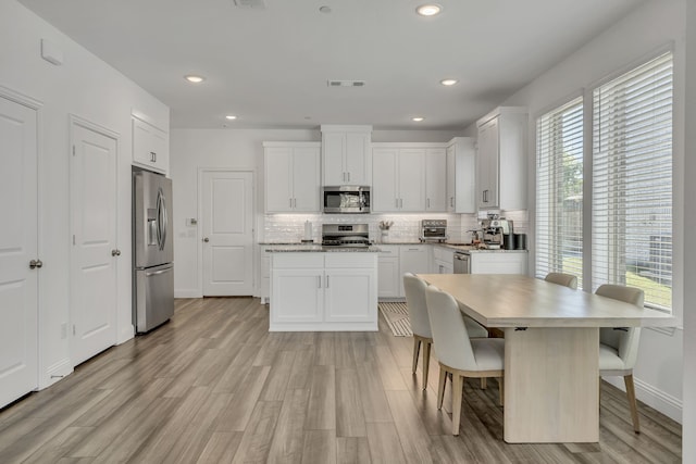 kitchen featuring a wealth of natural light, white cabinets, and appliances with stainless steel finishes