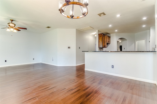 unfurnished living room featuring ceiling fan with notable chandelier and hardwood / wood-style flooring