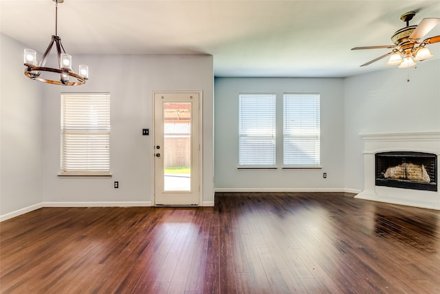 unfurnished living room featuring ceiling fan with notable chandelier and dark hardwood / wood-style flooring