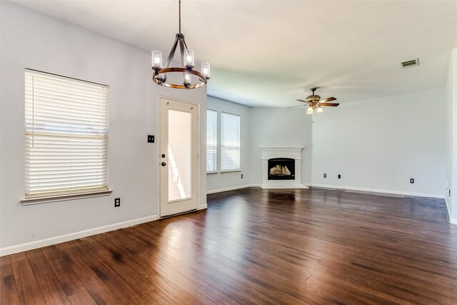 unfurnished living room featuring ceiling fan with notable chandelier and dark hardwood / wood-style floors