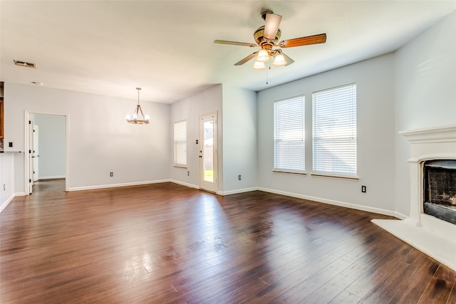 unfurnished living room featuring dark wood-type flooring and ceiling fan with notable chandelier