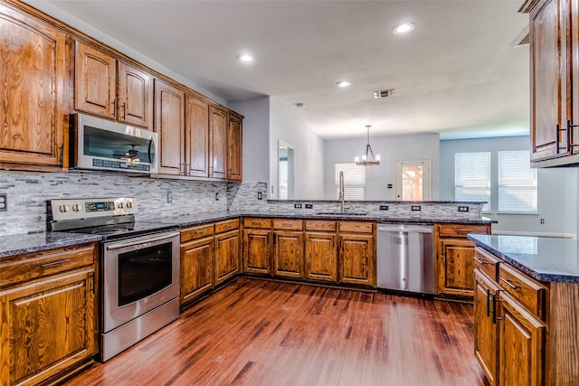 kitchen with stainless steel appliances, sink, decorative light fixtures, a notable chandelier, and dark hardwood / wood-style floors