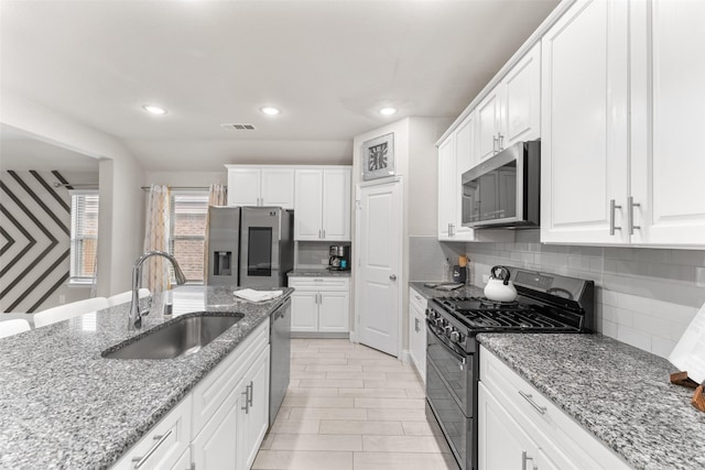 kitchen featuring white cabinets, sink, light stone countertops, appliances with stainless steel finishes, and tasteful backsplash