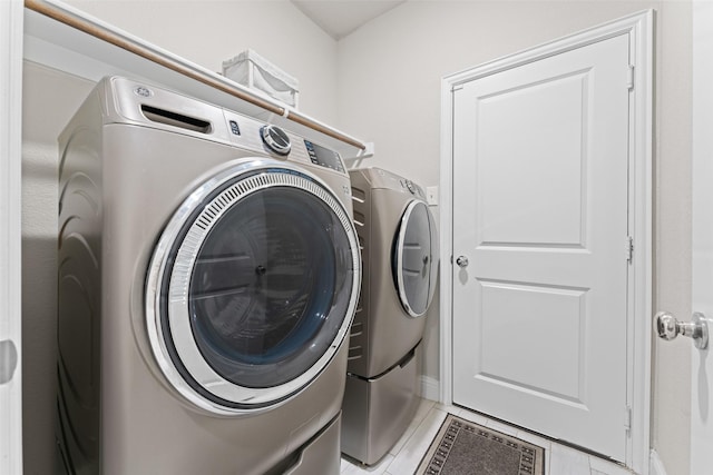 clothes washing area with light tile patterned floors and washer and dryer