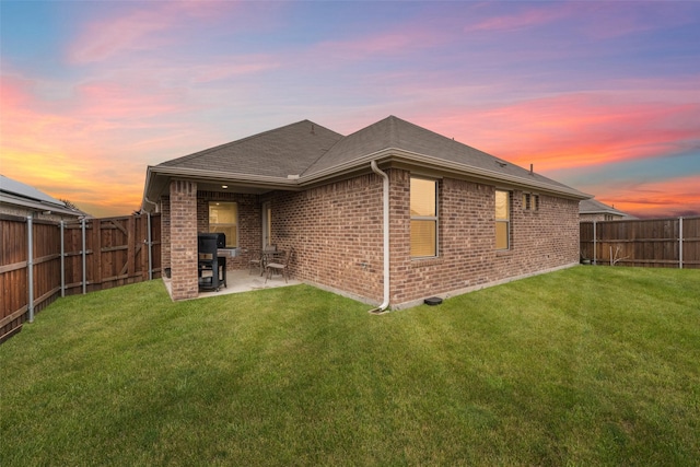 back house at dusk with a yard and a patio