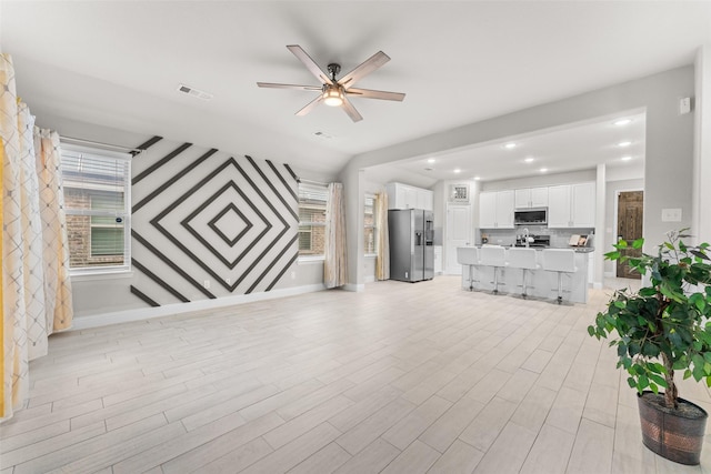 living room featuring vaulted ceiling, light hardwood / wood-style flooring, and ceiling fan