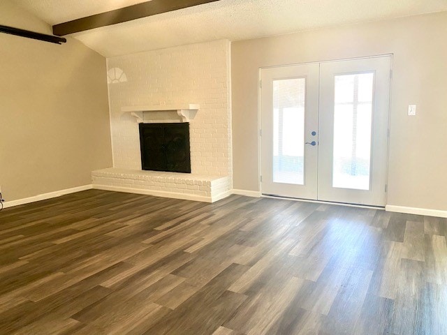 unfurnished living room featuring dark wood-type flooring, a fireplace, and french doors