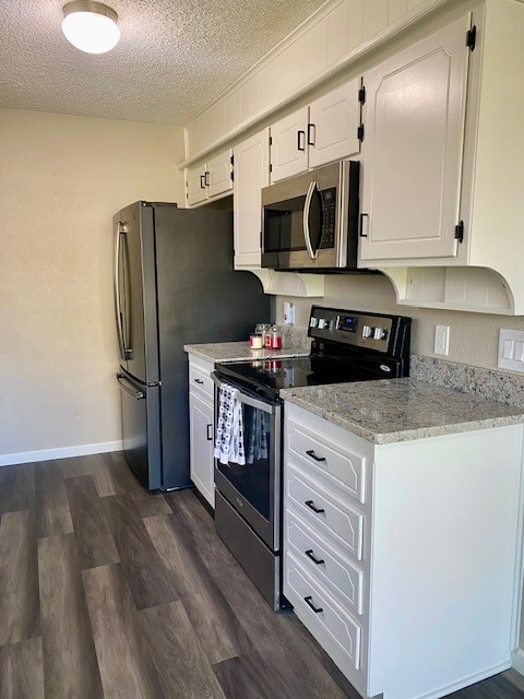 kitchen featuring light stone countertops, a textured ceiling, stainless steel appliances, dark hardwood / wood-style floors, and white cabinetry