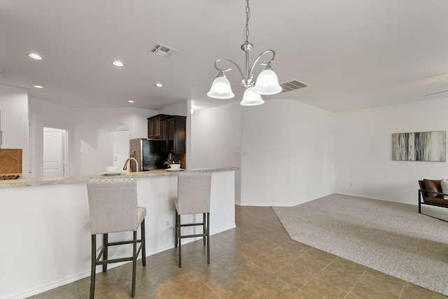 kitchen featuring pendant lighting, an inviting chandelier, a kitchen breakfast bar, stainless steel fridge, and kitchen peninsula