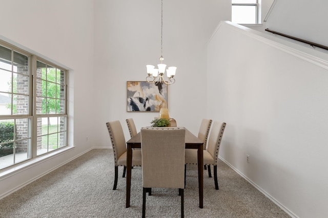 carpeted dining area featuring an inviting chandelier, plenty of natural light, and a high ceiling