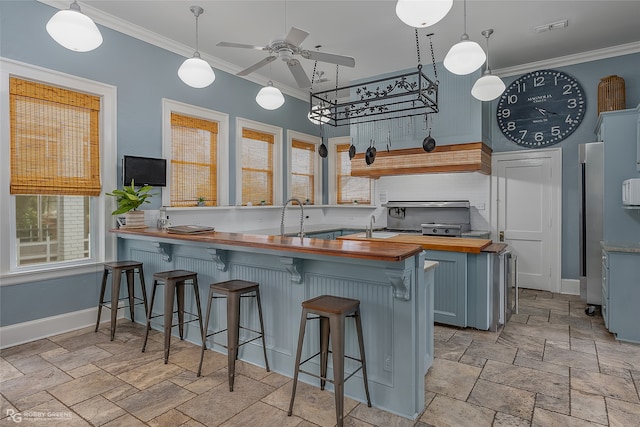 kitchen featuring pendant lighting, wooden counters, a breakfast bar, and kitchen peninsula