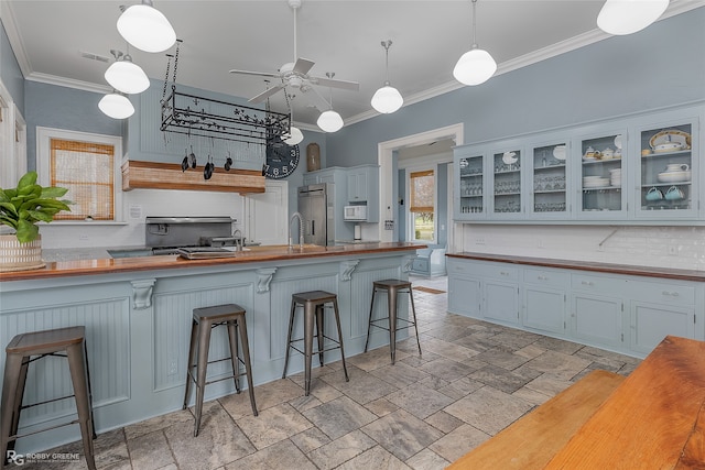 kitchen with backsplash, decorative light fixtures, a kitchen bar, and crown molding