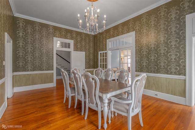 dining space with wood-type flooring, an inviting chandelier, and ornamental molding