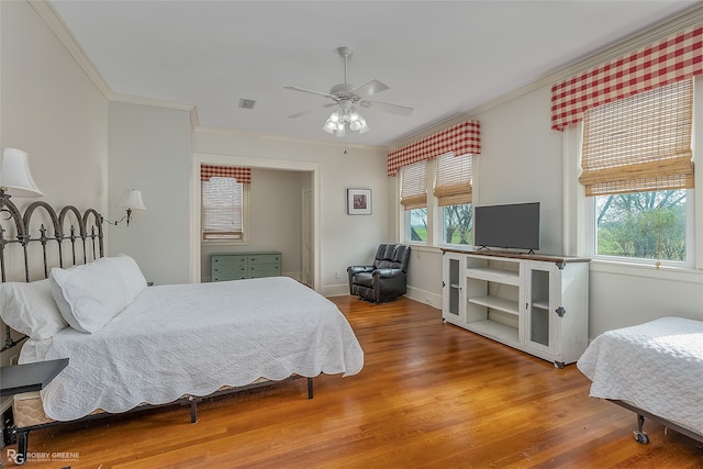 bedroom with crown molding, wood-type flooring, and ceiling fan