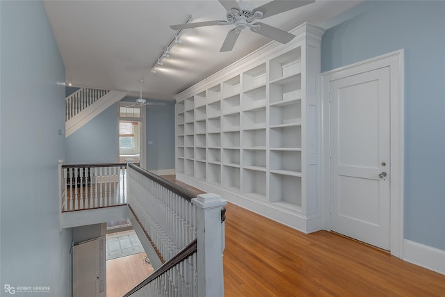 hall featuring rail lighting, built in features, and light hardwood / wood-style floors