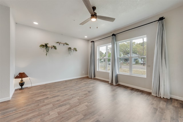 empty room with ceiling fan and light hardwood / wood-style floors