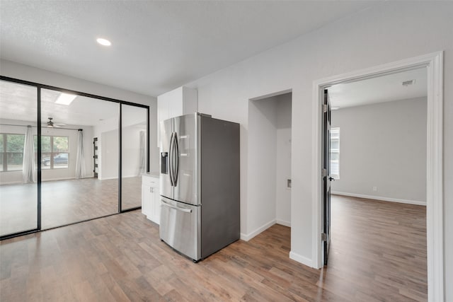 kitchen featuring stainless steel fridge, light hardwood / wood-style flooring, white cabinetry, and ceiling fan