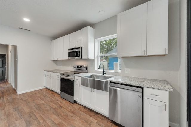 kitchen with sink, white cabinetry, stainless steel appliances, and light hardwood / wood-style flooring