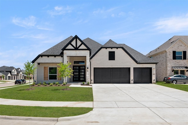 modern farmhouse style home featuring roof with shingles, an attached garage, a front lawn, brick siding, and concrete driveway