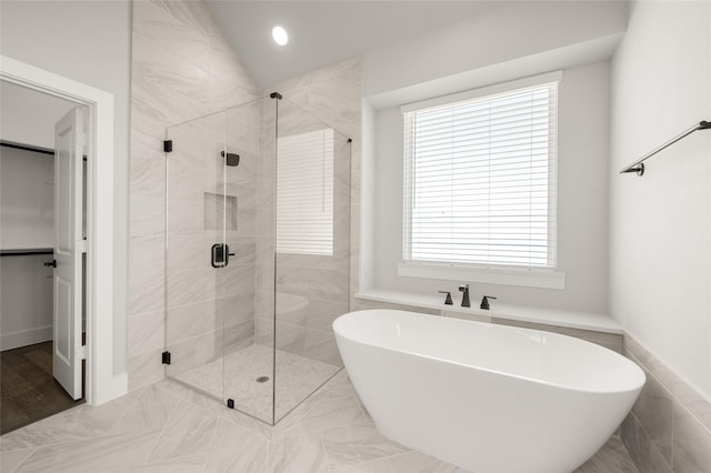 full bath with a freestanding bath, a shower stall, marble finish floor, and a healthy amount of sunlight