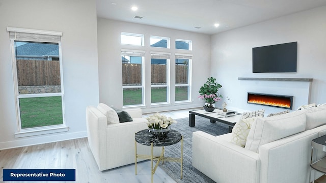 living room with a warm lit fireplace, recessed lighting, baseboards, wood finished floors, and visible vents