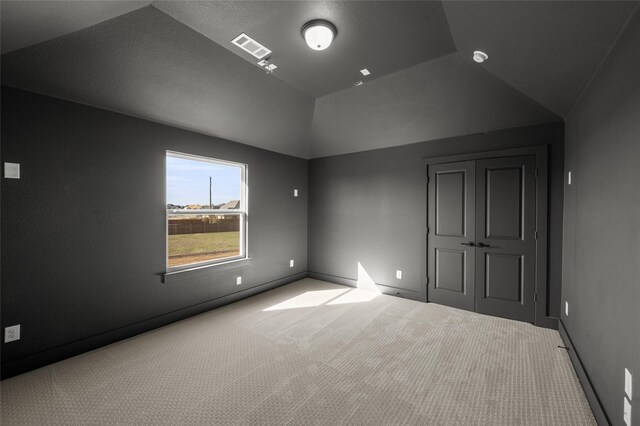 interior space featuring lofted ceiling, carpet floors, baseboards, and visible vents