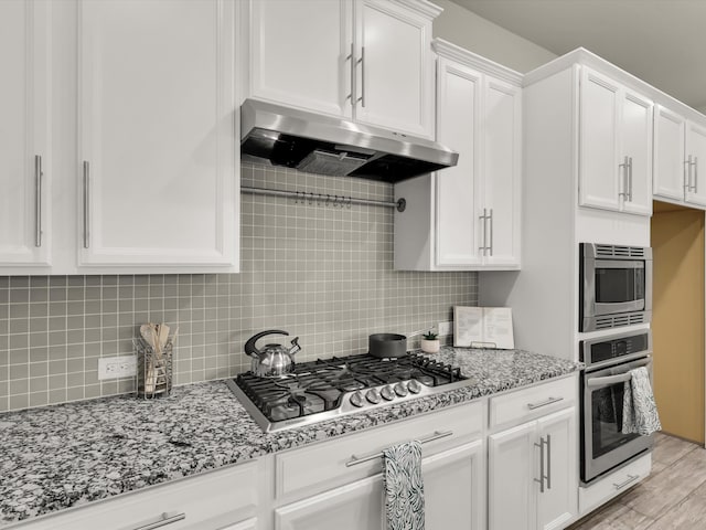 kitchen featuring light hardwood / wood-style floors, stainless steel appliances, backsplash, light stone countertops, and white cabinets