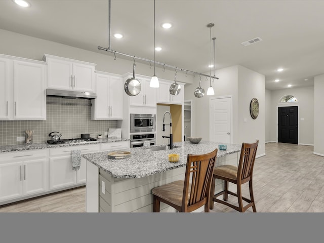 kitchen featuring sink, hanging light fixtures, a center island with sink, and stainless steel appliances