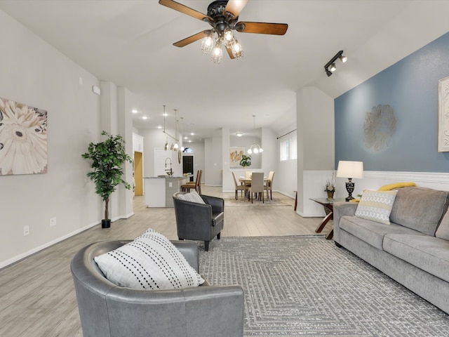 living room featuring ceiling fan with notable chandelier, light hardwood / wood-style floors, and sink