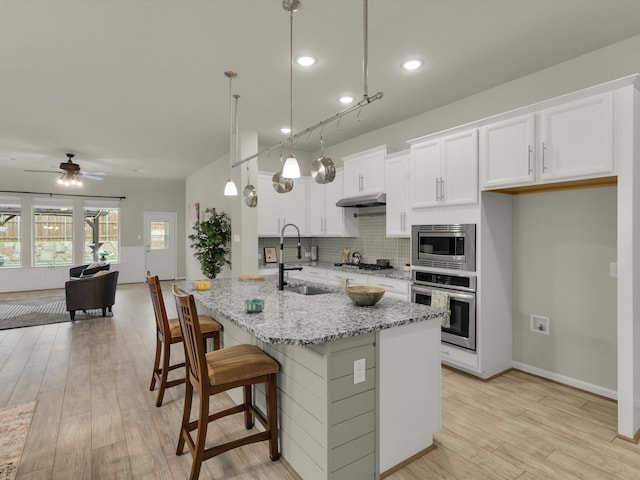 kitchen with appliances with stainless steel finishes, decorative light fixtures, white cabinetry, sink, and ceiling fan