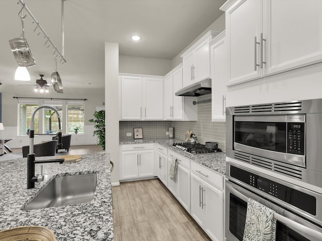 kitchen featuring white cabinets, appliances with stainless steel finishes, sink, and light stone counters