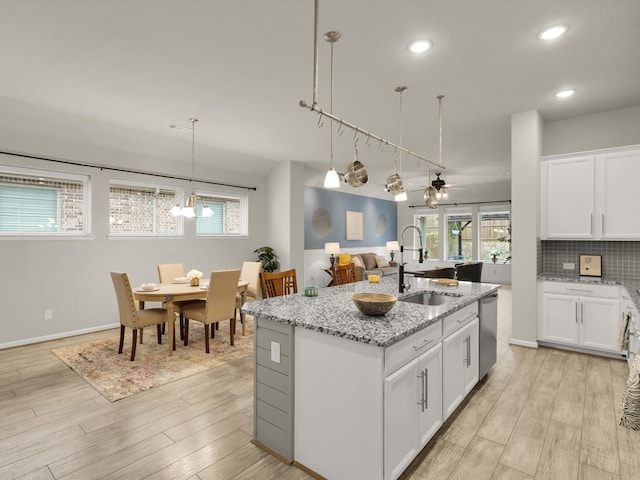 kitchen with white cabinets, a center island with sink, and sink