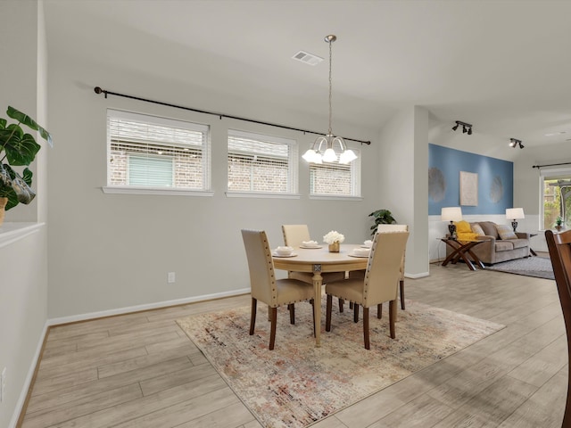 dining space with light hardwood / wood-style floors and an inviting chandelier