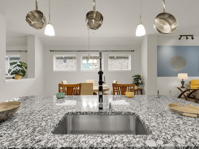 kitchen featuring decorative light fixtures, sink, and light stone counters