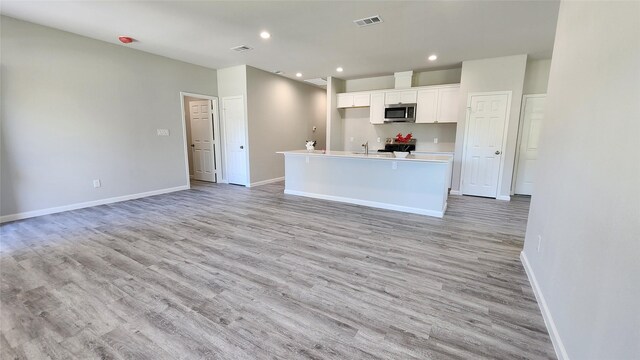 kitchen featuring a kitchen island with sink, light hardwood / wood-style flooring, white cabinets, and sink